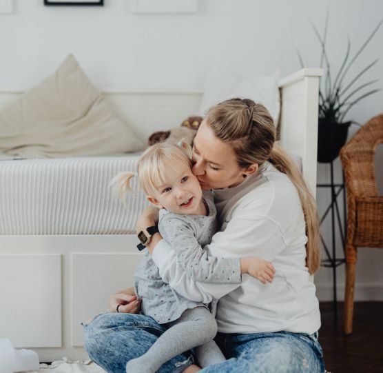 Mamma professionista che abbraccia i figli, per mostrare la scelta di confini gentili tra lavoro e famiglia.
